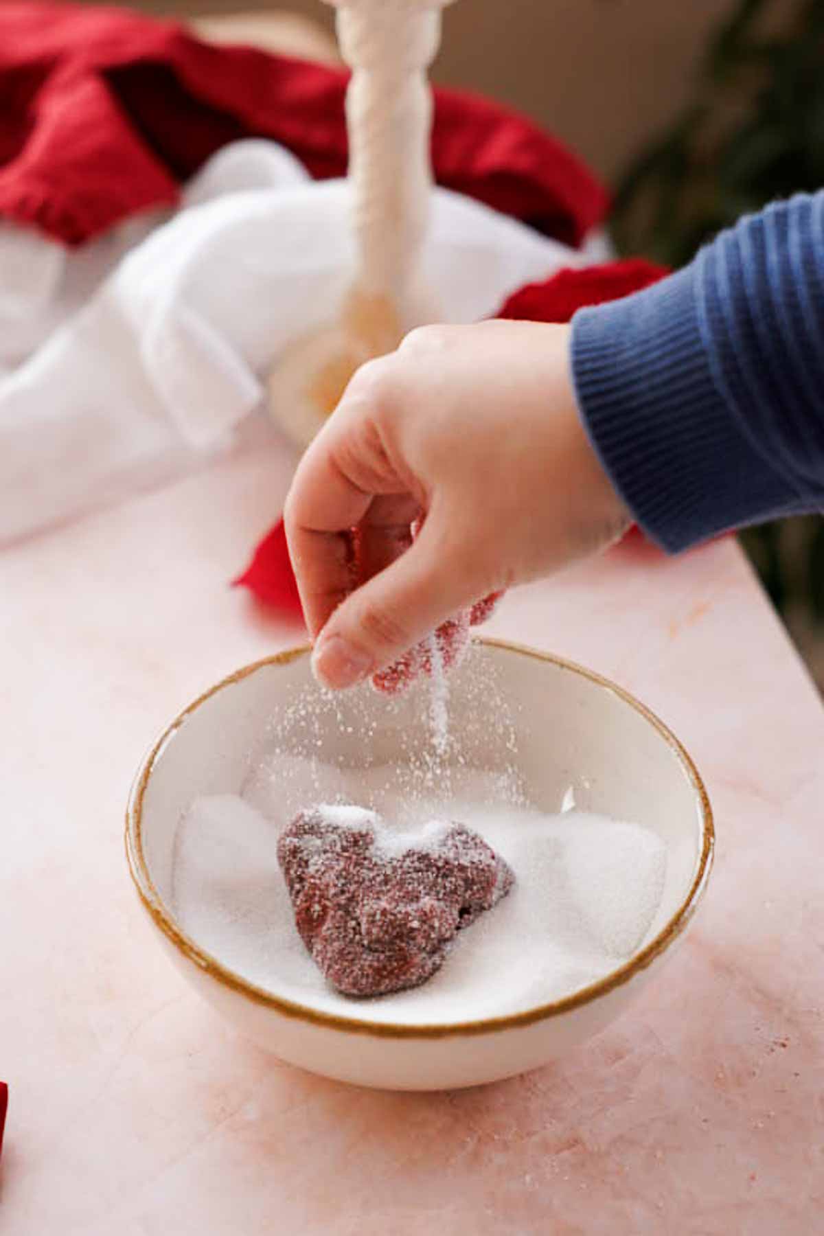 rolling red velvet cookie dough in sugar