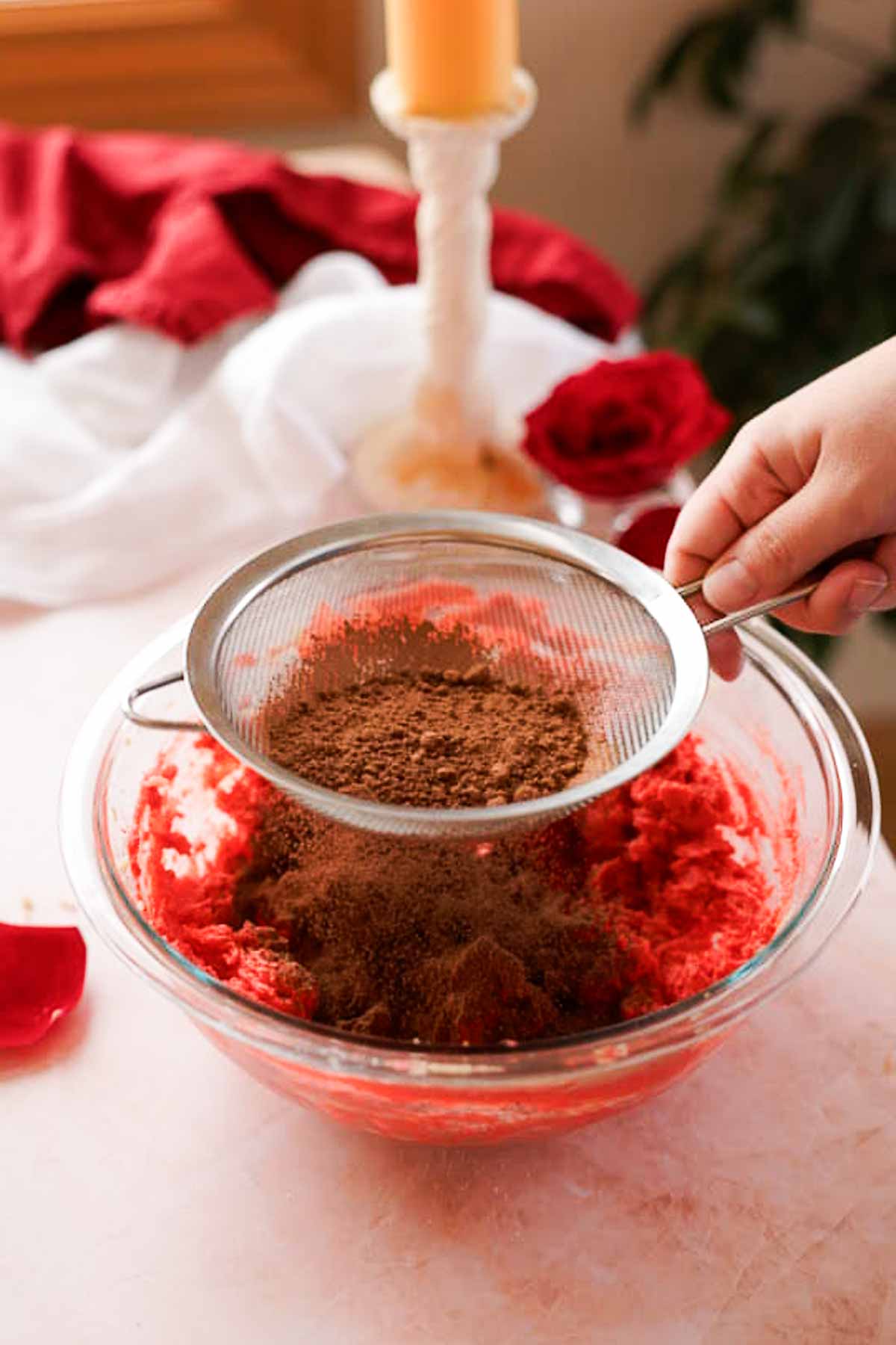 sifting cocoa powder into red velvet cookie dough