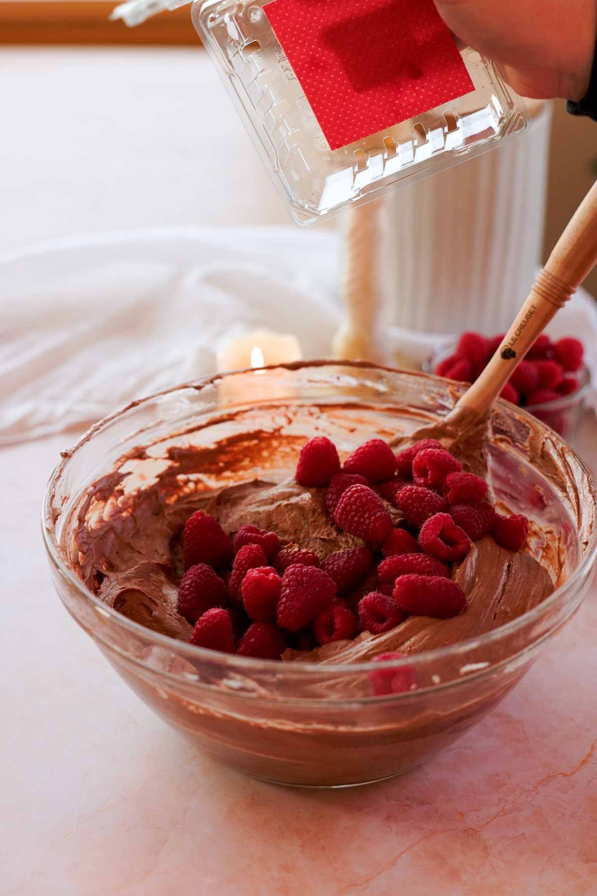 adding fresh raspberries into chocolate no bake cheesecake