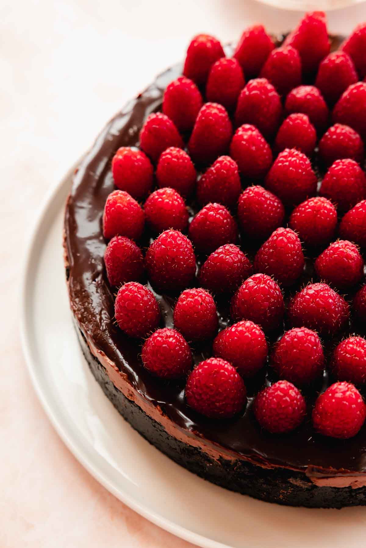 closeup of chocolate raspberry cheesecake with chocolate ganache and fresh raspberries on top