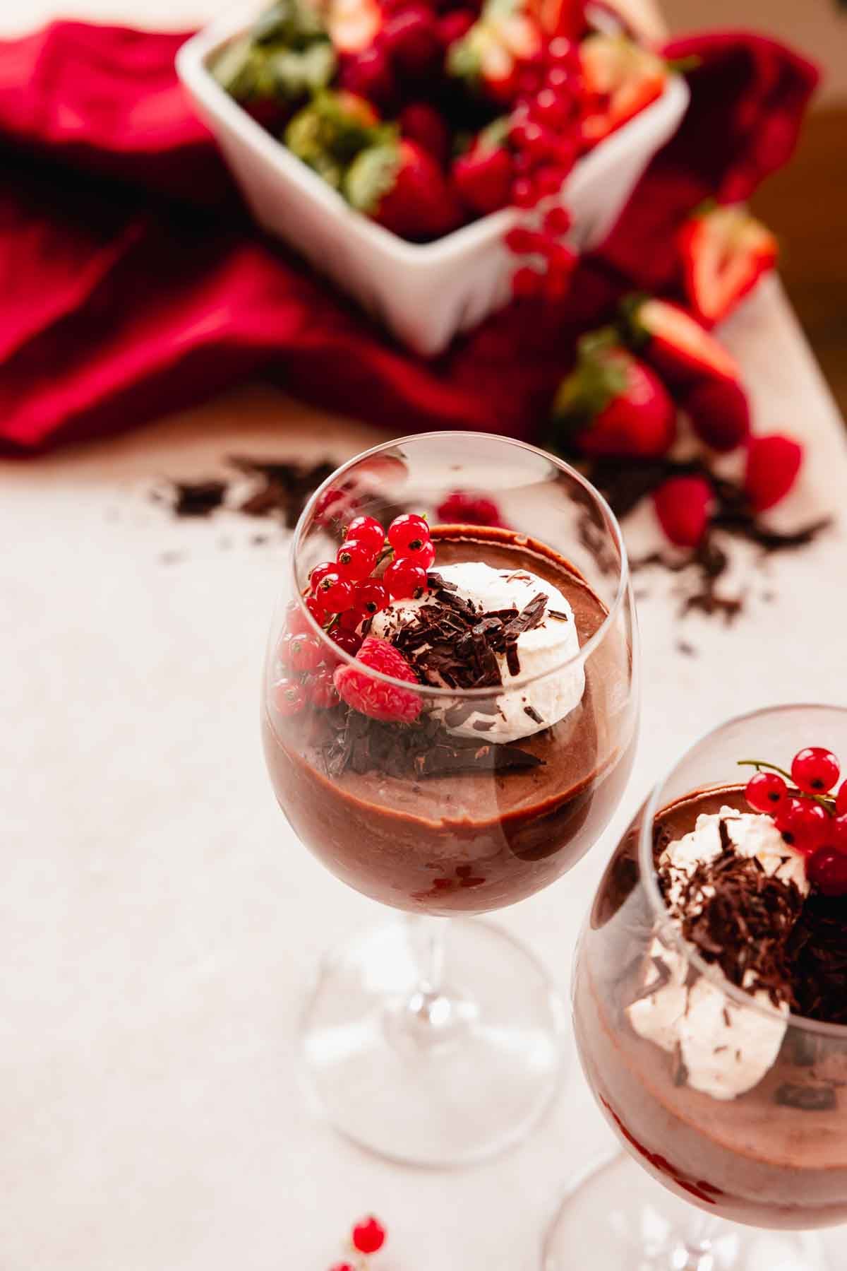 chocolate mousse in wine glasses with whipped cream and red berries
