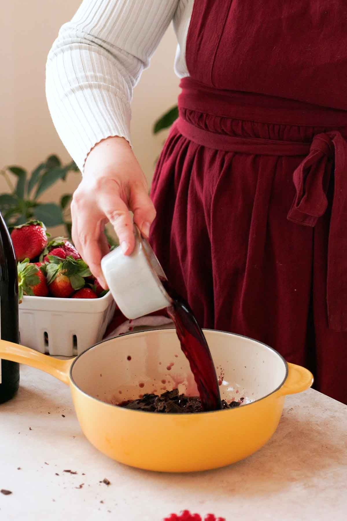 pouring red wine into chopped chocolate in saucepan