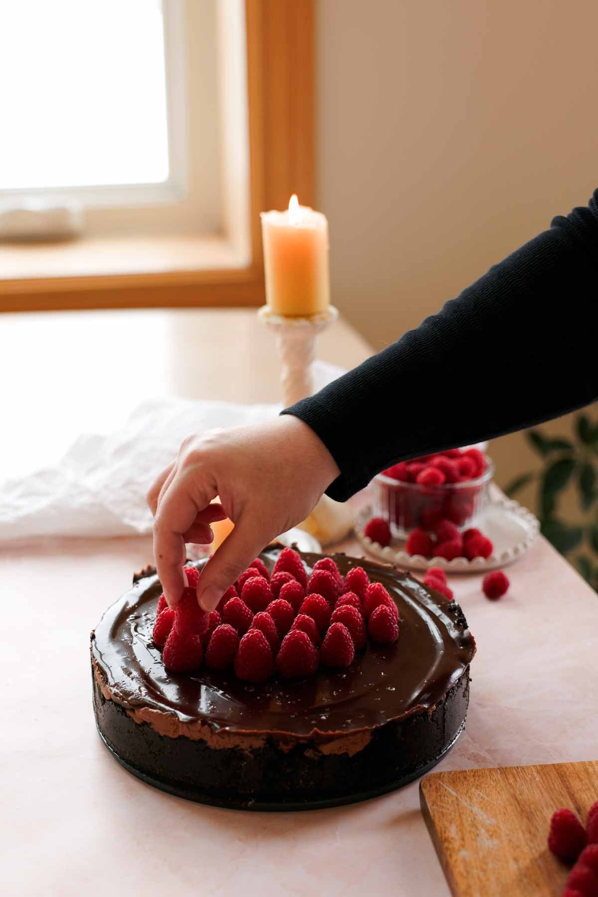 topping chocolate raspberry cheesecake with fresh raspberries