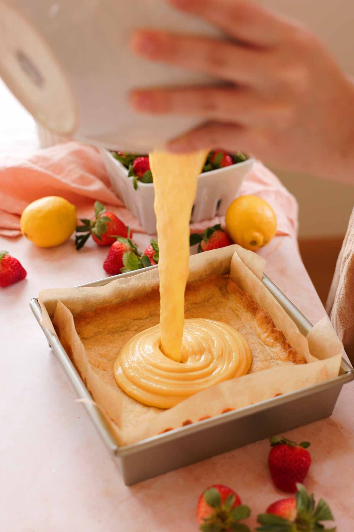 pouring lemon bar filling into baked shortbread crust