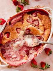 strawberry cobbler in a baking pan with cheesecake batter