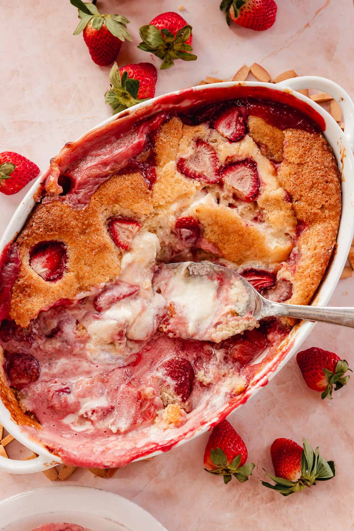 strawberry cobbler in a baking pan with cheesecake batter
