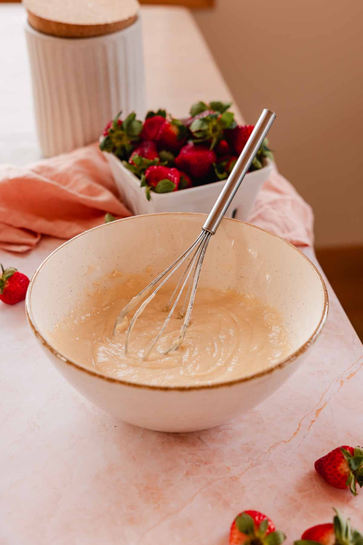 strawberry cobbler batter in a bowl with a whisk