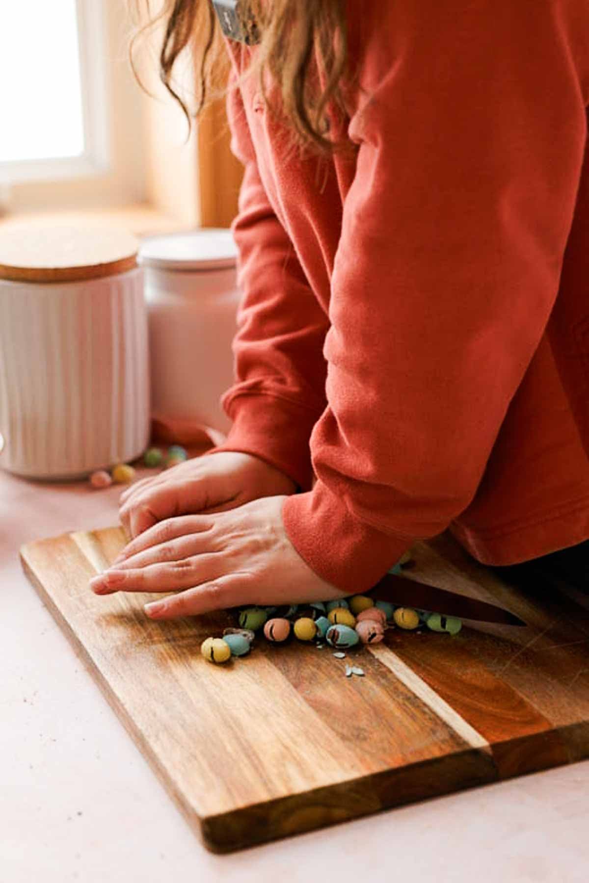 crushing mini eggs with flat edge of the knife on a cutting board