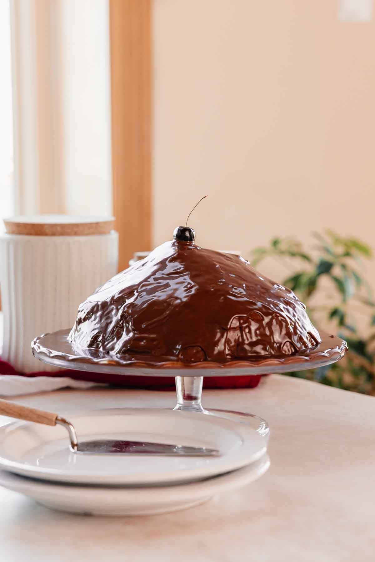 volcano cake covered in chocolate ganache with cherry on top