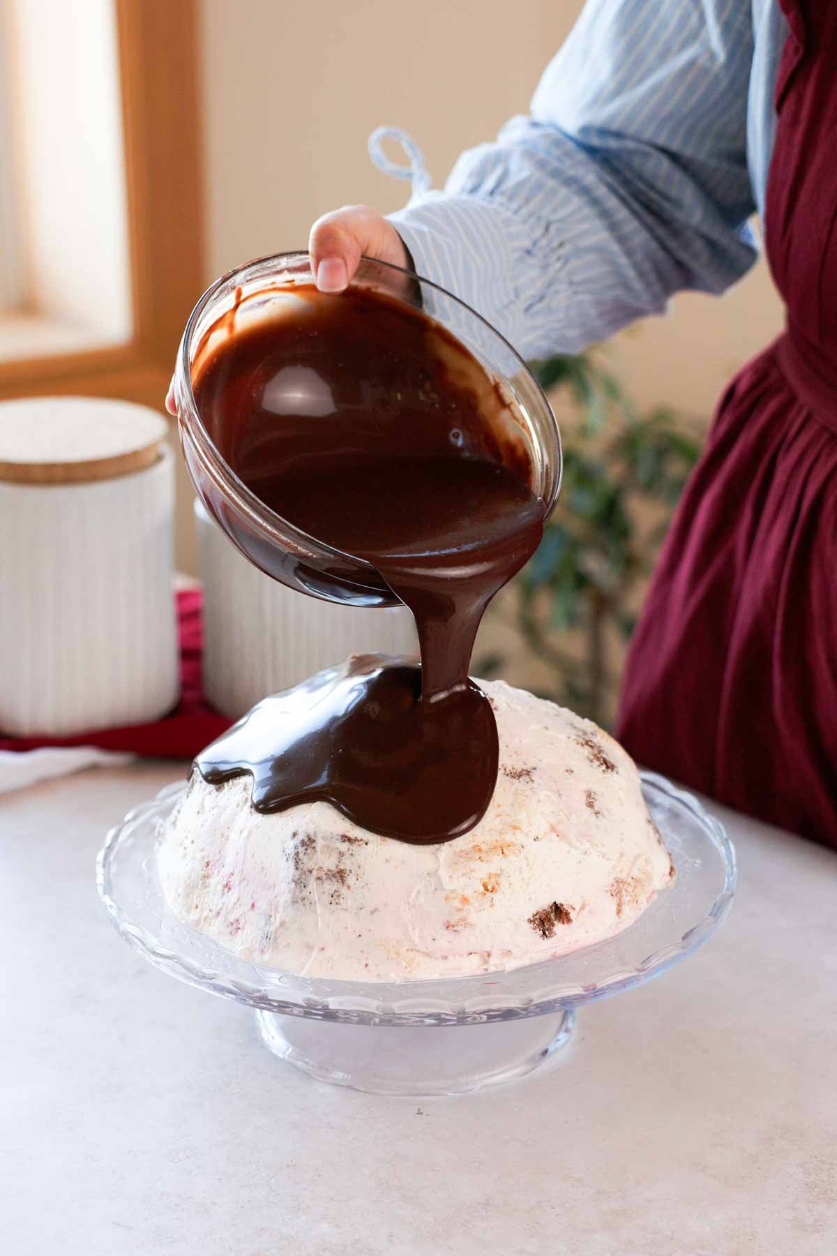 pouring chocolate ganache over volcano cake on cake stand
