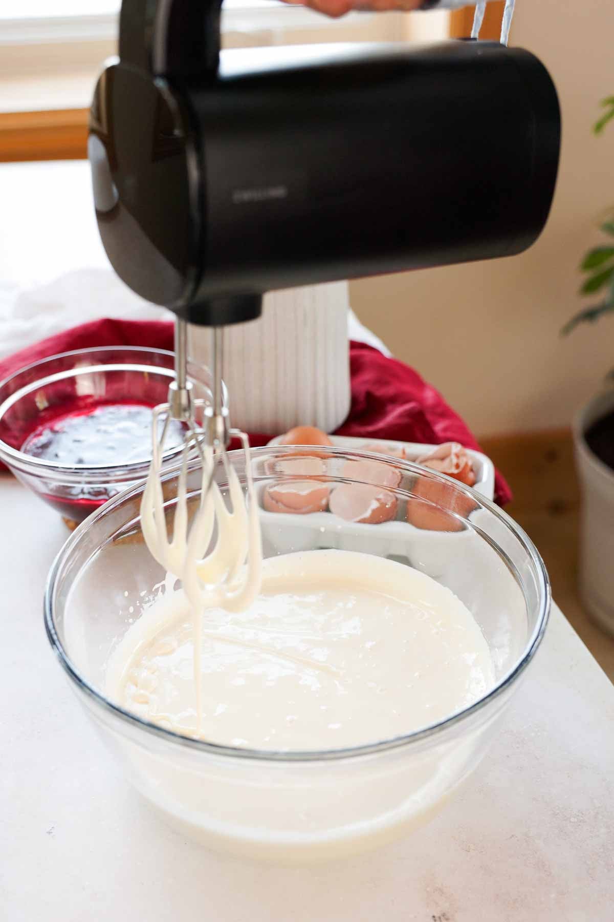 consistency of whipped eggs in ribbon stage in large glass bowl with electric mixer