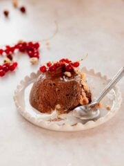 scoop of chocolate hazelnut mousse on plate with red currant and hazelnut pieces