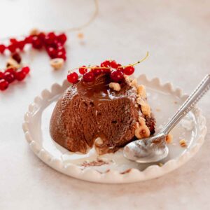 scoop of chocolate hazelnut mousse on plate with red currant and hazelnut pieces