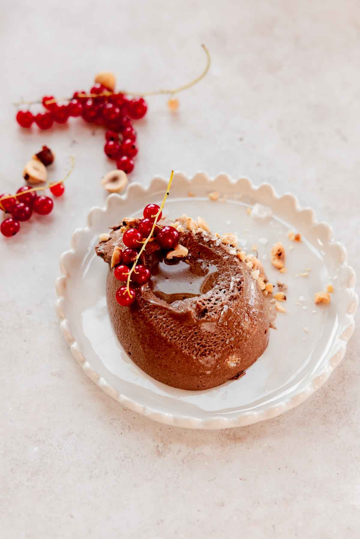 scoop of chocolate mousse on serving plate with berries and flaky salt and oil