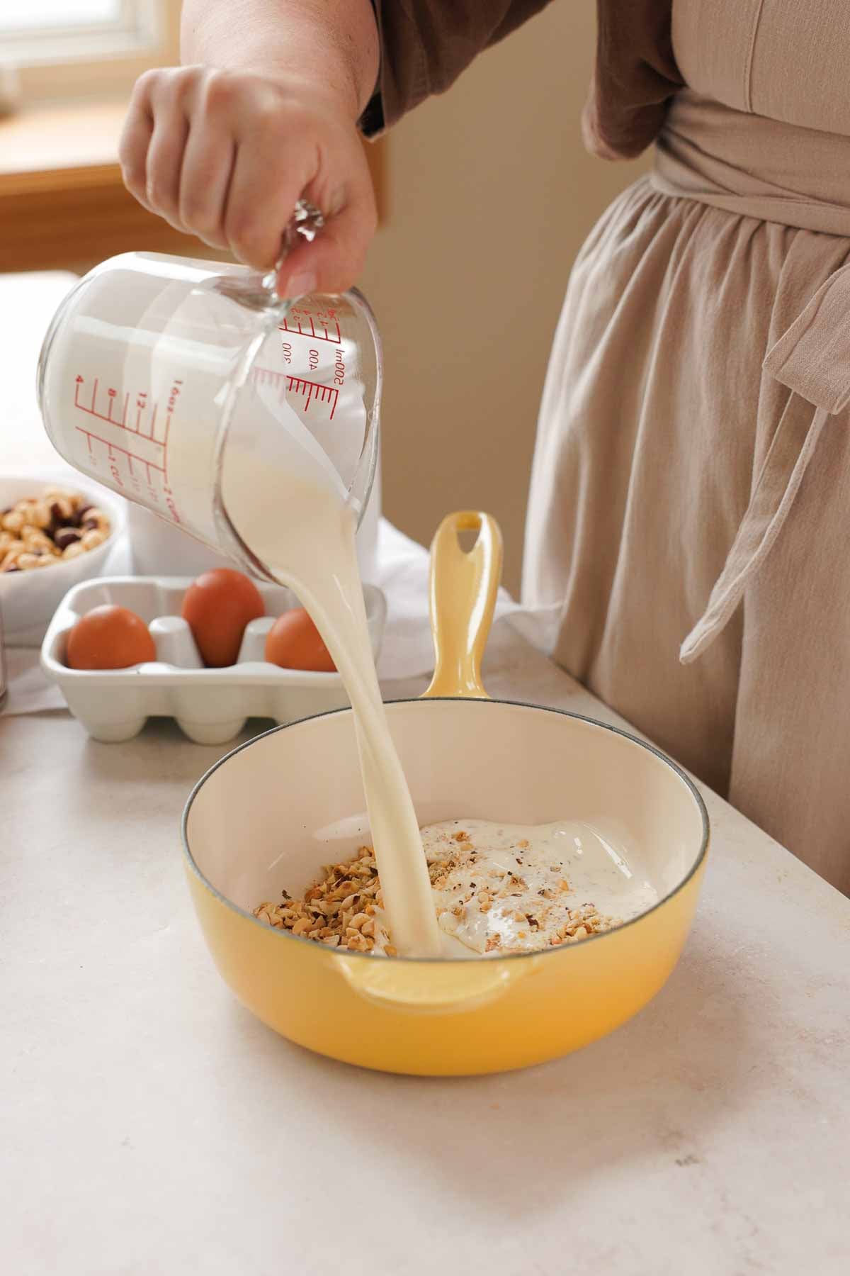pouring cream from measuring cup into saucepan