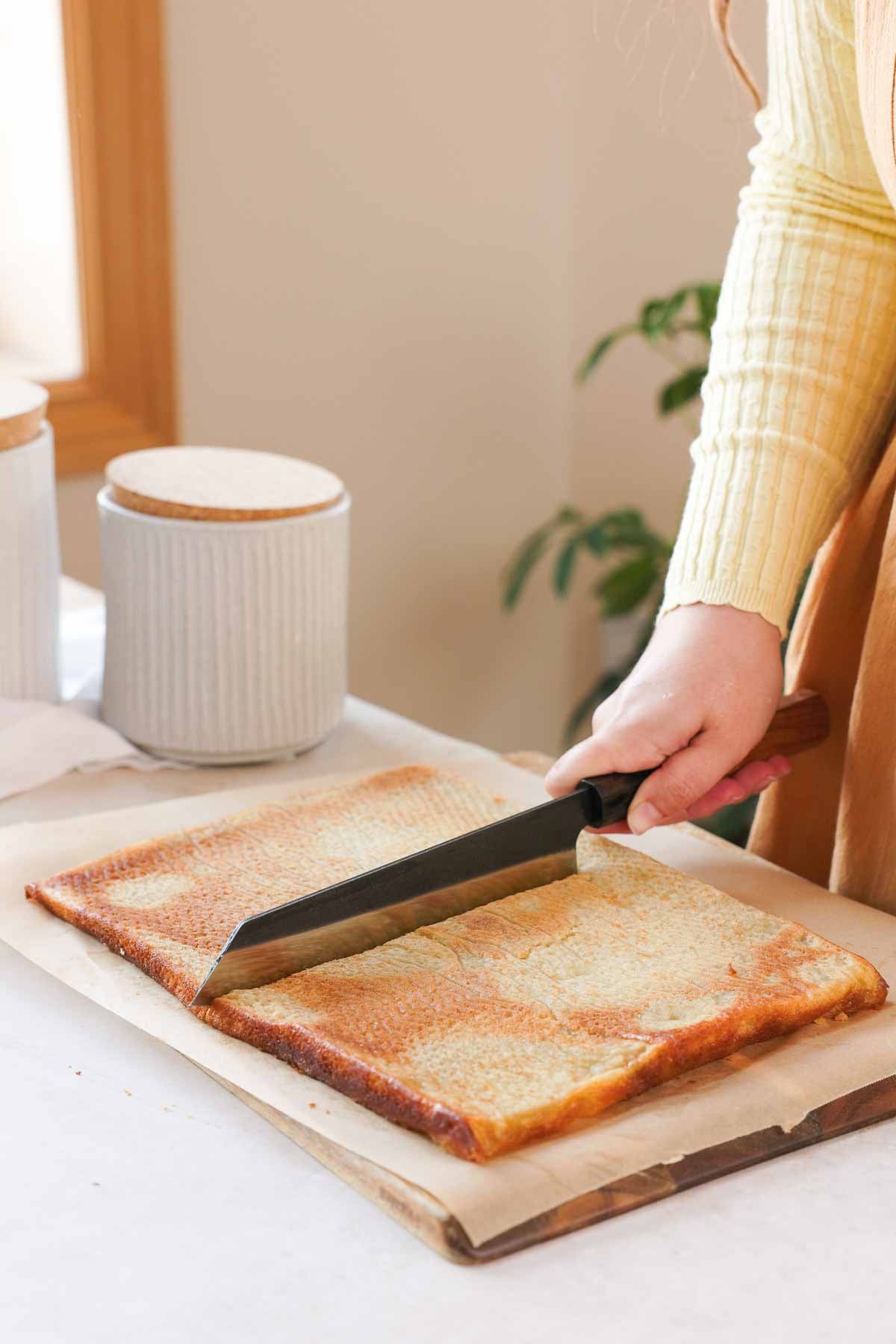 cutting baked butter mochi in half with large knife