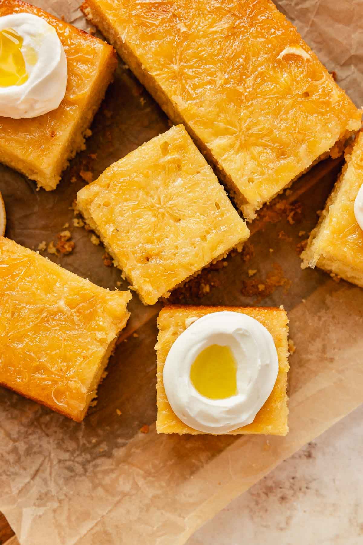 upside down lemon olive oil cake pieces with yogurt whipped frosting and olive oil drizzle