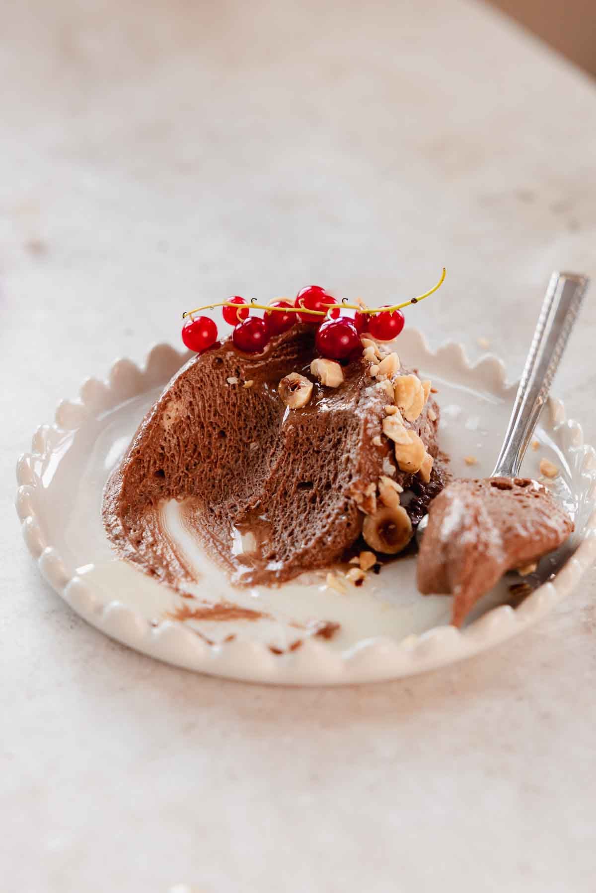 scoop of chocolate mousse with hazelnuts on plate with bites taken from it