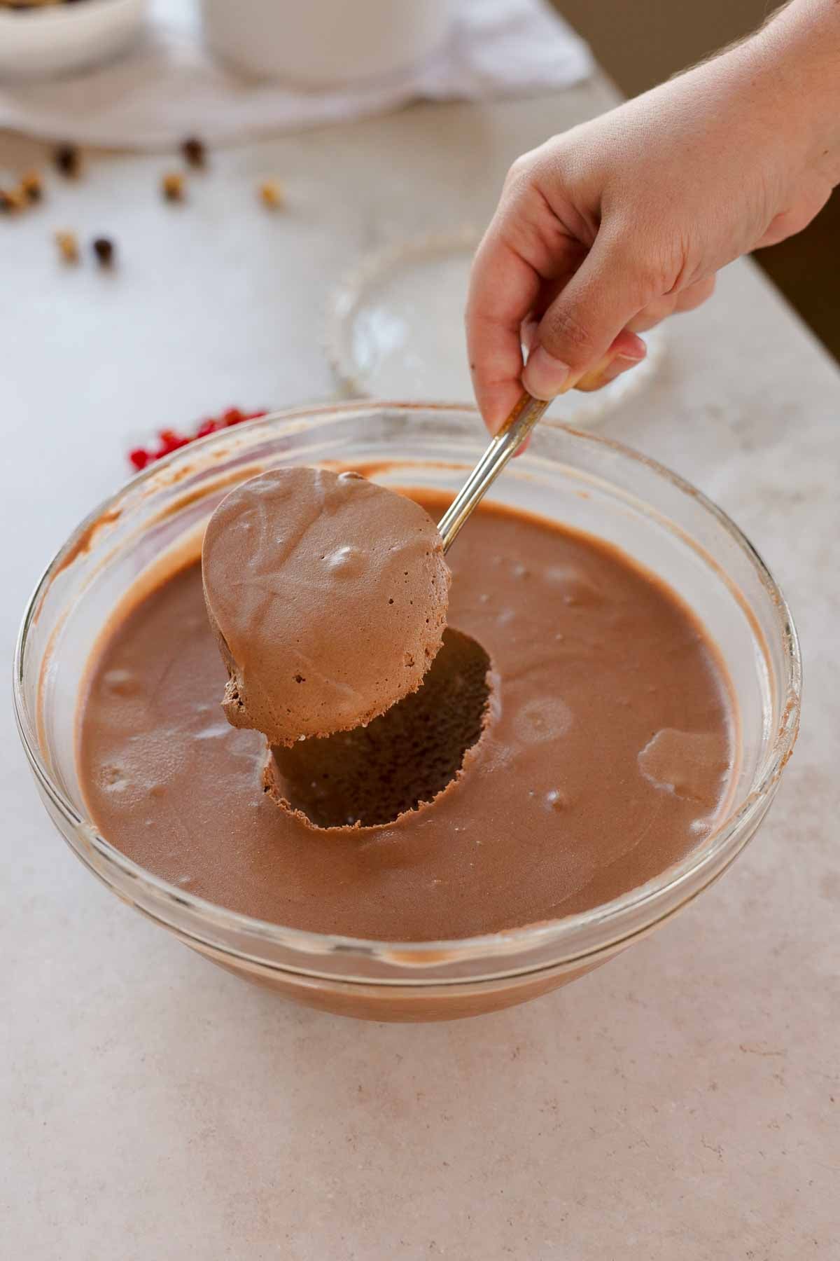 scooping chocolate hazelnut mousse from large glass bowl with a large spoon