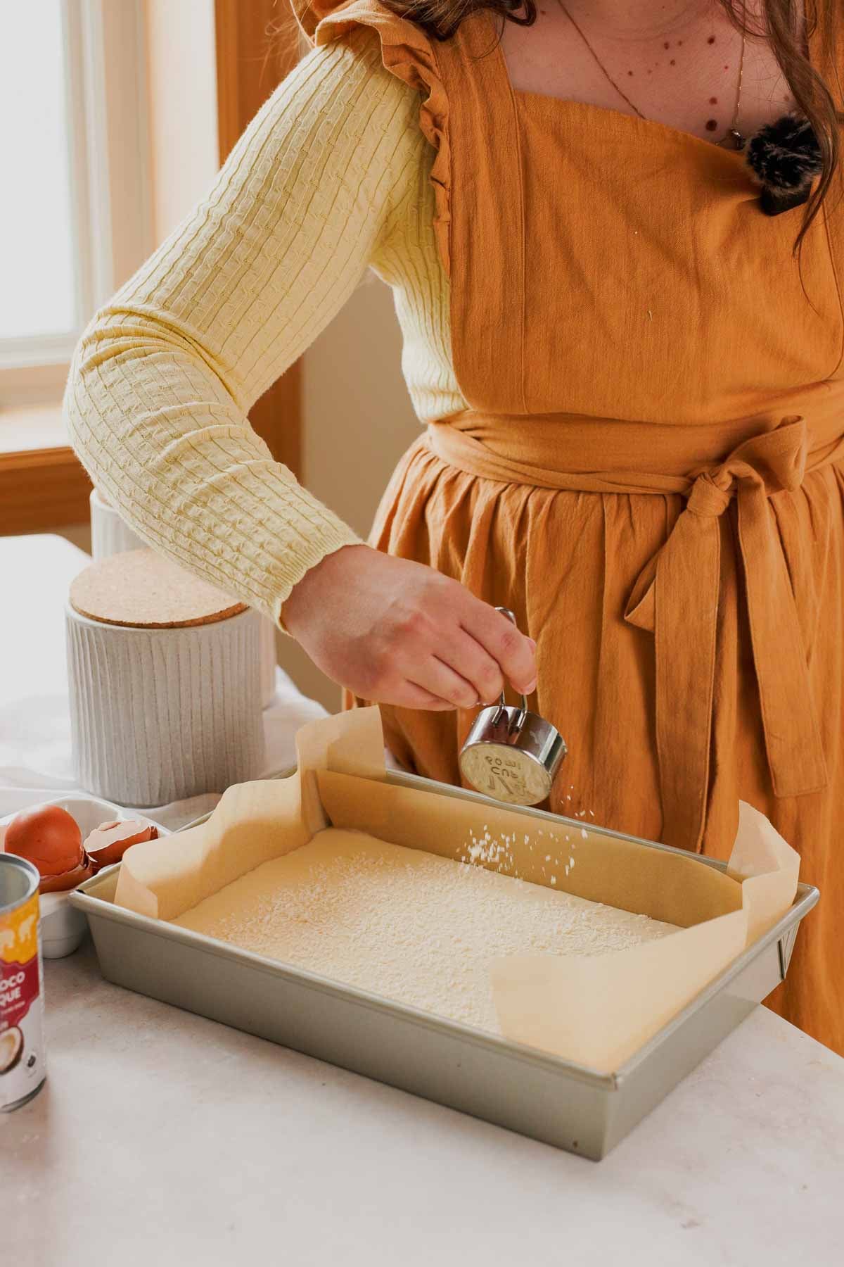 sprinkling shredded coconut onto butter mochi batter