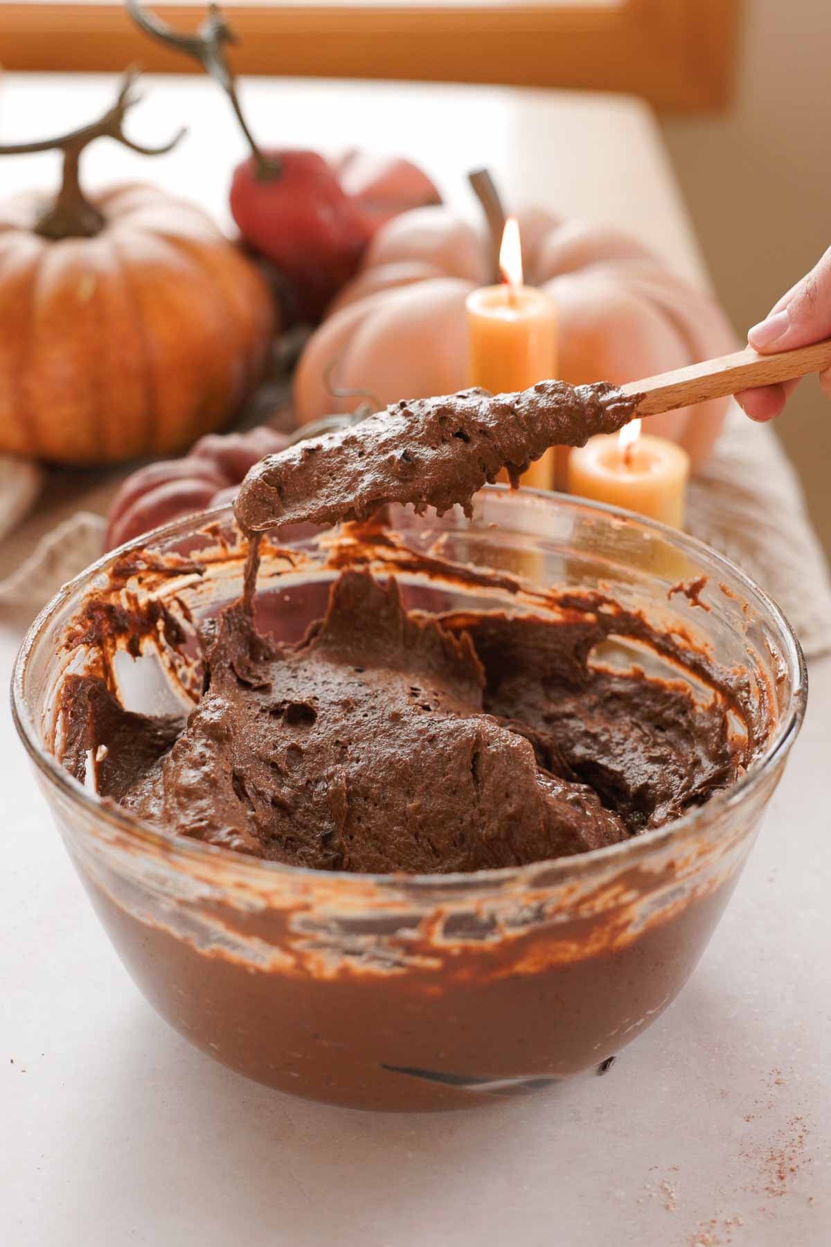folding pumpkin chocolate cake batter in large glass bowl with silicone spatula