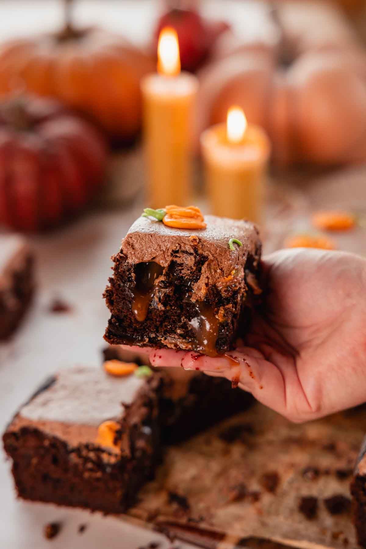 holding slice of moist pumpkin chocolate cake with gooey caramel in hand