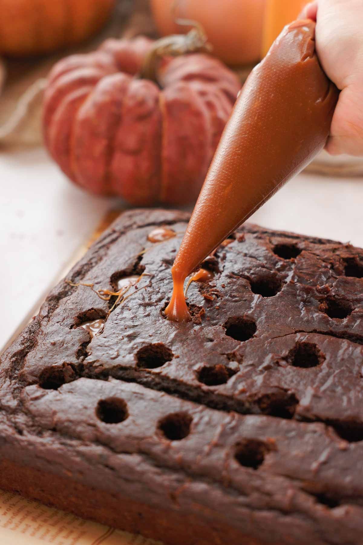 filling holes in chocolate cake with salted caramel in piping bag