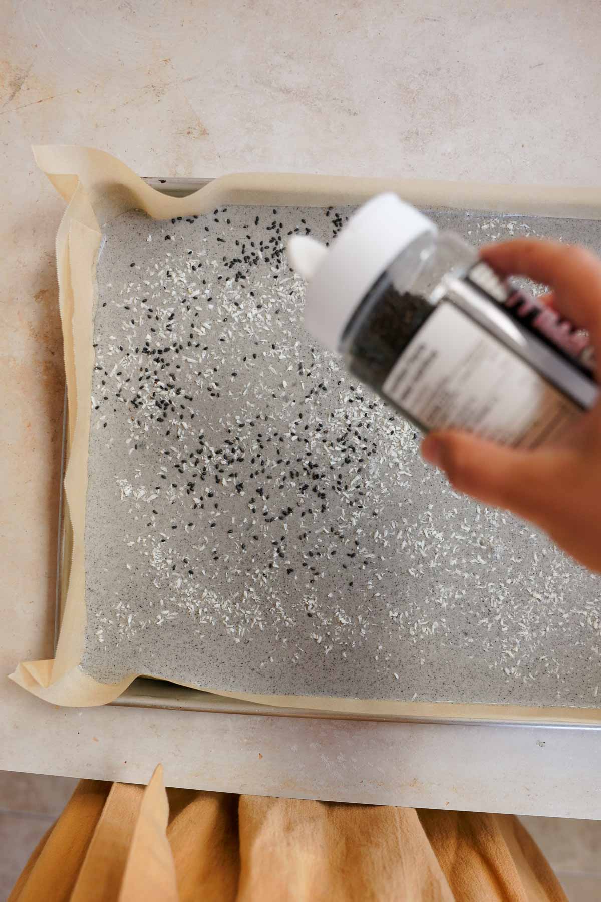 sprinkling sesame seeds onto black sesame mochi
