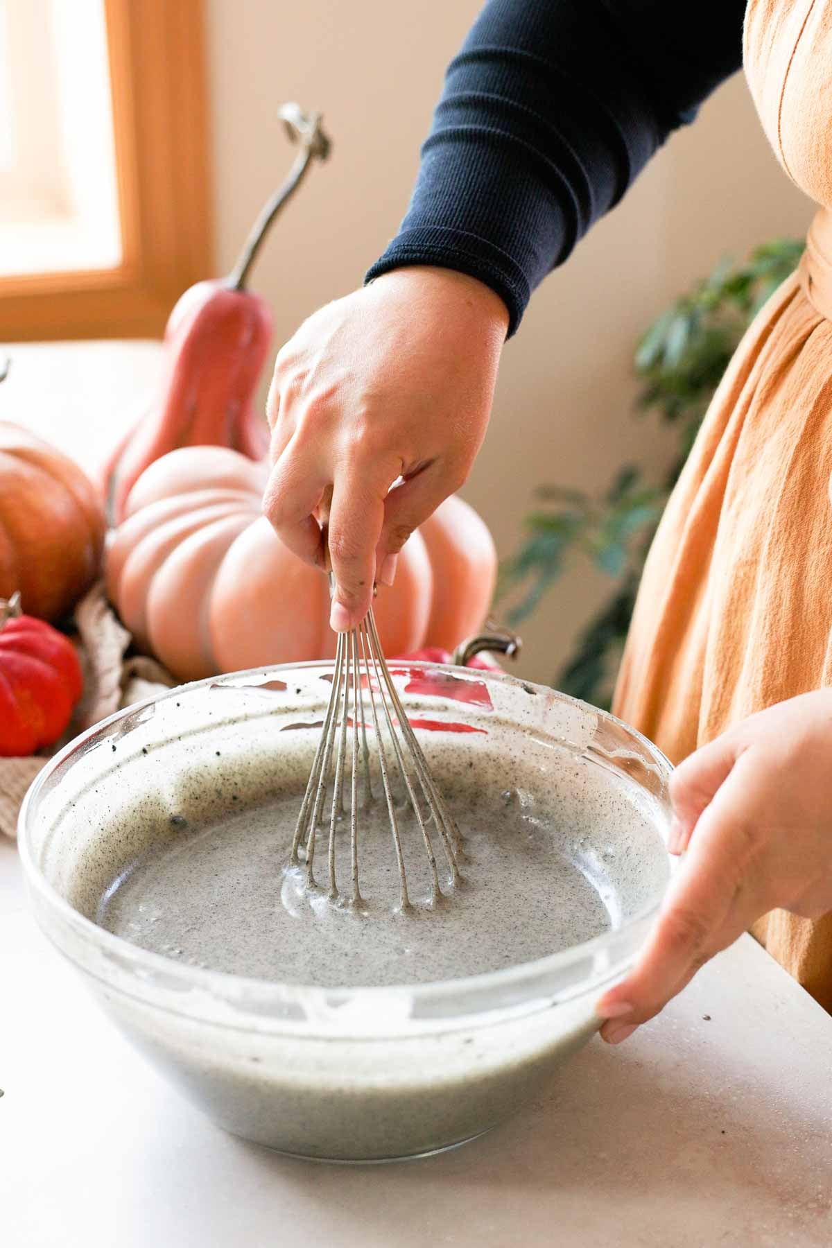 whisking black sesame butter mochi batter in large glass bowl